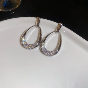 Macro shot of silver teardrop hollow earrings with inlaid sparkling zircon stones