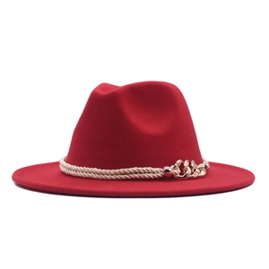 Détail d'un chapeau fedora rouge avec corde tressée beige et chaîne dorée décorative