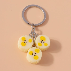 Close-up of fruit-themed keychains with white round resin charms on a peach background