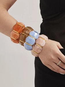 Gros plan de bracelets en résine colorée avec des accents dorés sur le poignet d'une femme