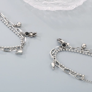 Detailed macro view of silver astronaut and heart magnetic pendants on double-layered chain