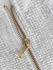 Vue macro d'une fermeture éclair dorée sur un tissu argenté texturé de robe bandage