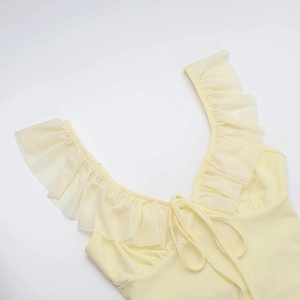 Detail view of light yellow ruffle trim and delicate drawstring tie on the summer dress