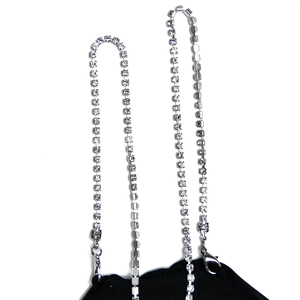 Détail de bretelles en strass argentés avec fermoirs métalliques sur tissu noir