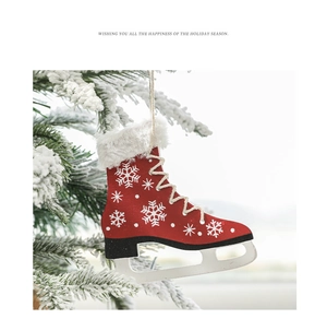 Detail of red wooden ice skate ornament with snowflake patterns on a snowy tree branch