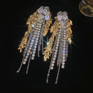 Elegant gold leaf and diamond chain fringe drop earrings on a luxury black velvet background