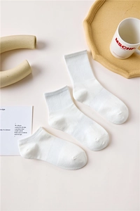 Three pairs of white cotton mid-calf and short socks shown on a minimalist wooden tray
