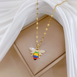Close-up of golden necklace featuring a rainbow enamel bee pendant with pavé crystals