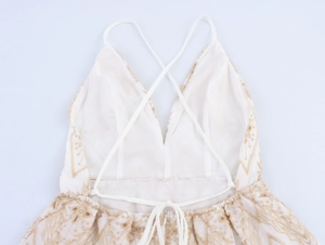 Detail of cross back straps and golden floral embroidery on a white vacation dress