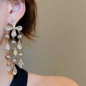 Close-up of silver tassel earrings with crystal teardrops worn by a female model