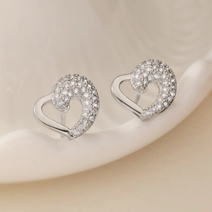 Fashionable silver heart stud earrings with sparkling cubic zirconia on ceramic tray