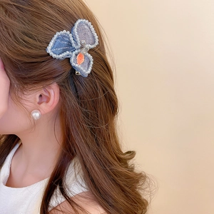 Close-up of blue beaded floral hair clip with crystal sequins on brown wavy hair