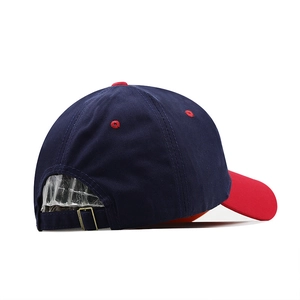 Detail view of the navy baseball cap with red brim showing metal buckle strap and embroidery