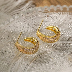 Detail of C-shaped gold-plated earring with pave-set pink zircon on glass tray