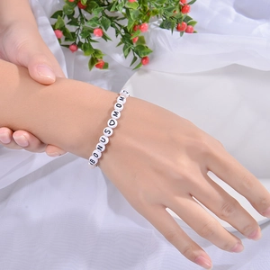 Close-up of Bonus Mom beaded bracelet with white acrylic beads on soft fabric background