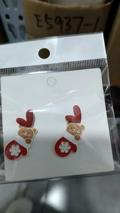 Detailed view of Christmas earrings with cute brown bears in red snowflake gloves and hearts