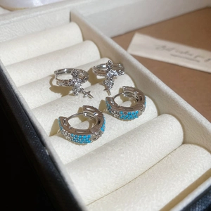 Detail of silver cross earrings with zircons and turquoise stone huggie hoop earrings