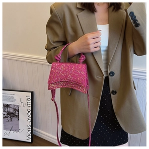 Detailed view of pink sequin trapezoid handbag with knotted handle and shoulder strap
