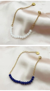 Detail of beaded bracelets with white and dark blue beads on an elegant silk background