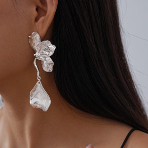 Close-up of a large silver metallic butterfly petal earring worn by a female model