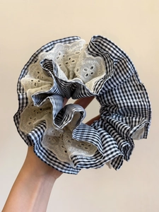 Close-up of oversize houndstooth hair scrunchie with white eyelet lace trim detail