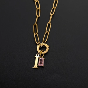 Detailaufnahme einer vergoldeten Edelstahlkette mit rosa Edelstein und dem Buchstaben I