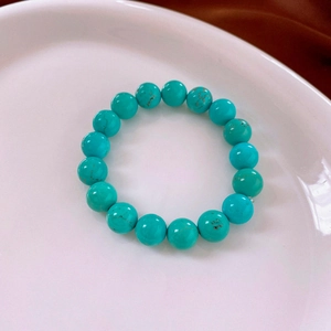 Macro shot of turquoise beads with natural black veins on a clean white ceramic plate