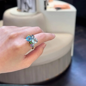 Detail of 18K gold ring featuring multi-colored cluster gemstones on a model's hand