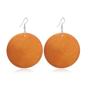 Gros plan sur le grain de bois naturel des boucles d'oreilles rondes orange