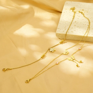 Detailed close-up of gold clover and butterfly bracelets on white stone and silk