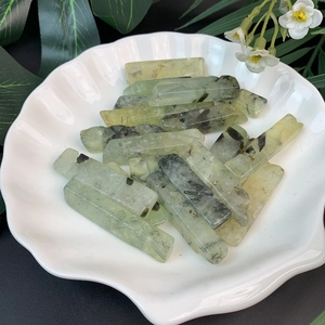 Macro detail of natural green prehnite stone pendants in a white shell-shaped dish