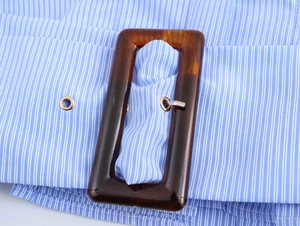 Detail of blue and white striped fabric belt with a tortoiseshell square buckle and eyelet