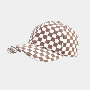 Close-up of brown and white checkerboard pattern on cotton baseball cap with curved brim
