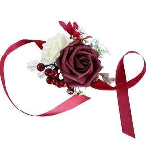 Bridal wrist corsage with burgundy roses, white berries, and long satin ribbon for weddings