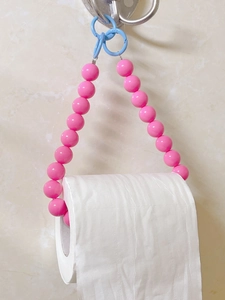Detail of pink beaded toilet paper holder with light blue rings on white wall