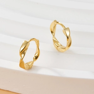 Detail of S925 hallmark on golden Mobius twist hoop earrings with polished finish