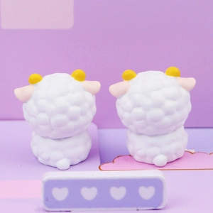 Close-up of two cute white sheep figurines with yellow horns and pink ears on a purple base