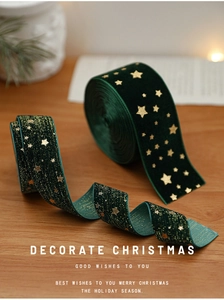 Detail of dark green velvet Christmas ribbon with gold star prints on wooden surface
