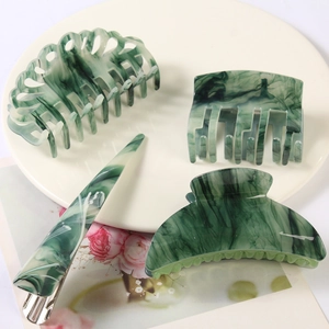 Green marble acetate hair claw clip and barrette set displayed on a white plate