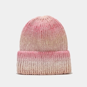 Gros plan sur la texture en maille épaisse dégradée rose et beige du bonnet d'hiver