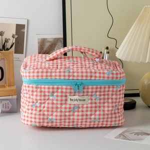 Quilted checkerboard cosmetic bag with orange-white grid and small blue bow patterns