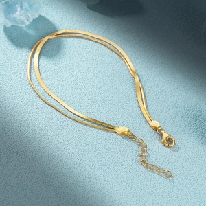 Detail shot of a S925 sterling silver stamp on a double-layer golden snake chain bracelet