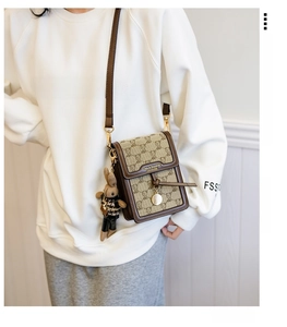 Detail of a brown crossbody bag with teddy bear pattern and cute bunny plush charm