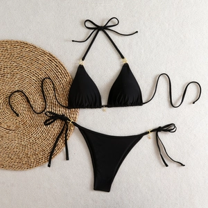 Detailed flat lay of black triangle bikini featuring golden star metal charms and side ties
