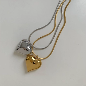 Close-up of gold and silver heart pendants on square snake chains in 45-degree view
