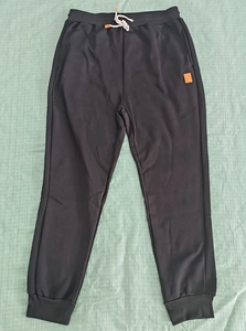 Detail view of black sweatpants with off-white drawstring and elastic waistband