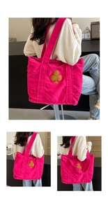 Detail of rose red canvas tote with yellow club patch and frayed tassel edges