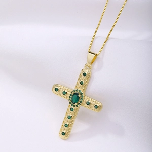 Detailed macro view of a vintage gold cross pendant with green emerald zircon inlays