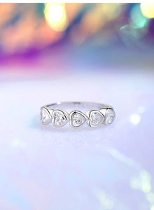 Close-up of five heart-shaped cubic zirconia stones on a polished silver band