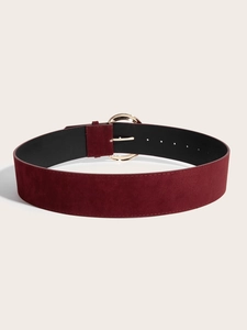 Détail d'une ceinture en daim bordeaux avec boucle ronde dorée polie et trous réglables